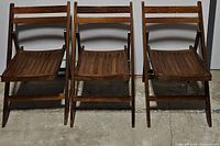 Front view of three wooden folding chairs with slatted seats and backs, showing their structure and folding mechanism.