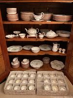 Wood cabinet shelf displaying stacks of plates, bowls and assorted serving pieces