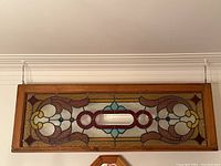 Front view of rectangular stained glass transom window in wooden frame