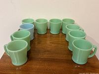 Ten mugs arranged in circle: nine green Jadeite and one blue Delphite