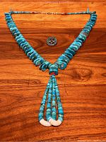 Full view of necklace laid flat with brooch positioned above center