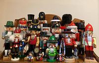 Overview of 20 full sized and 3 miniature nutcrackers displayed on wood bench