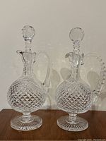 Two matching crystal decanters side by side showing full profile and matching diamond-cut bodies