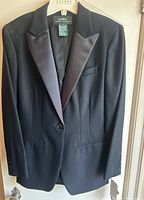 Front view of black women's tuxedo jacket by Ralph Lauren on hanger with satin peak lapels and single button