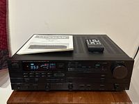 Front view of receiver powered on with manual and remote on top