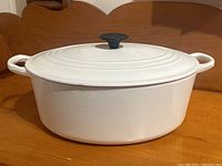 Front side profile of white oval Dutch oven showing both side handles and overall shape