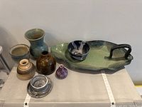 Seven ceramic items: 5 vases of various shapes and glazes, 2 bowls, and a large green tray with a handle