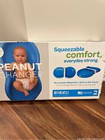 Box packaging of Peanut Changer showing infant model and product features, highlighting squeezable comfort and no laundry needed.