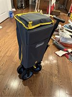 Front view of Coleman wagon showing fabric body with yellow trim, handle and wheels.