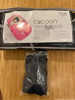 Front label showing product name '7 A.M. Enfant Cocoon' with image of pink cocoon on infant car seat and product details.