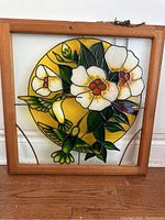 Front view of stained glass suncatcher with floral and hummingbird design, in wooden frame.