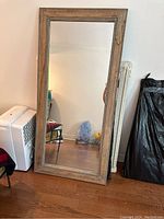 Front view of large full-length mirror with wooden frame showing reflective surface and wood accented with gold bead details.