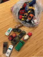 Plastic bag with assortment of toy vehicles including military-style jeeps, trucks, and classic cars.