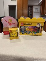 Front view of the lot showing Lego Classic storage box, Lego storage head container in box, and floor puzzle packaging with ballerina image