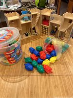 Melissa & Doug wooden castle playset displayed open with plastic connecting vehicles spilled in front on a wood table surface.