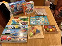 Overview of all puzzles including boxed floor puzzles and various wooden sound puzzles with vehicle, dinosaur, and instrument themes.