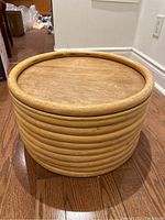 Side view of round wooden floor table showing stacked wooden rings on base and circular top with rounded edge.
