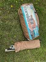 Tent and poles in carry bags laid out on grass with visible branding and product image on the bag.