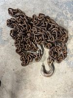 Photo showing heavy-duty steel logging chain coiled on the floor with a large metal hook visible at the end.