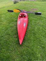 Top view of red kayak on grass with three paddles laid across cockpit
