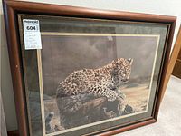 Framed print of a baby jaguar resting on a log, visible detail of artwork and frame