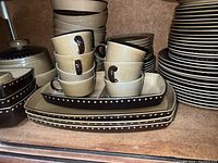Stoneware cups, rectangular serving dishes, butter dish, and lidded container on shelf.