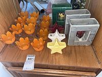 View of all items including lotus flower dessert cups, orange tulip teacups, square pottery planters and Masonic star small vases, arranged on wooden shelf.
