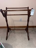 Full frontal view of the vintage wooden quilt rack showing the three horizontal bars and turned wooden legs