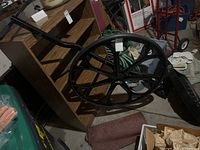 Wheeled snow shovel laid on the floor near shelving and storage items showing large black wheel and handle.