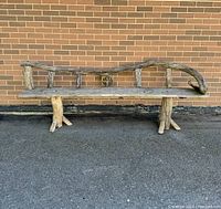 Full view of the handmade garden bench showcasing the branch and plank construction with natural wood textures.