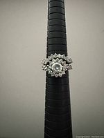 Front view of nestling rings set on ring sizer showing central large clear stone and surrounding smaller stones