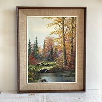 Full view of the framed vintage oil painting showing the colorful forest scene with lake, rocks, and trees, signed by R. Schul.