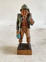 Front view of the hand carved wooden folk art figurine showing the man holding a bottle and axe.