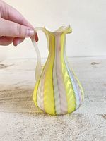 Image showing the vase held in hand to indicate size and the colorful herringbone pattern on the curved body with mother of pearl satin finish.