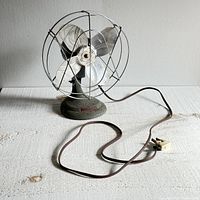 Side angle view showing metal blades, circular wire protective cage, power cord, and textured base.