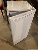 Full view of white Danby bar fridge with door slightly open, showing exterior condition.