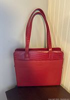 Front view of red leather tote bag with shoulder straps, showing crocodile embossed leather detail on upper section and smooth leather lower body.
