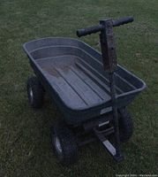 Full view of the garden cart on grass showing the heavy plastic tub, metal frame, handle, and tires.