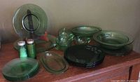 Photo showing all green glass tableware items including plates, cups, saucers, oval platters and serving dishes, butter dish and salt and pepper shakers.