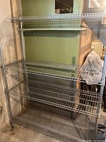 Front view of the IKEA Omar metal shelving unit showing four wire grid shelves and metal posts with adjustable height.