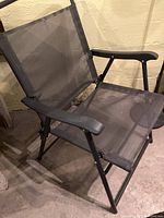 Side and top view of one grey metal frame folding lawn chair with mesh seat and backrest, showing armrest and frame structure.
