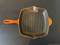 Top view of Le Creuset grill pan, showing the square shape with ridged cooking surface and orange handle.