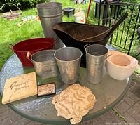 Full lot overview on glass table showing all pots, plaques, and coal scuttle outdoors with grass background.