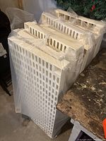 Plastic shelving panels wrapped in plastic, showing side profile and ventilation slots.