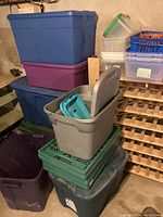 Plastic storage containers and totes of various colors and sizes stacked showing many are with lids.