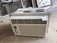 Front perspective of Zenith window air conditioner showing vent, control panel, and overall unit in garage setting.