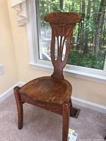 Full view of antique oak chair showing carved backrest, shaped seat with visible wood grain and crack.