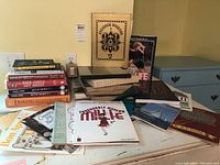 Various books including cookbooks, songbooks, and related genres arranged on a table.
