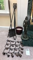 Photo showing metal fireplace tools (shovel, poker, tongs), ceramic planter, metal sculpture of Blind Lady Justice, and metal chimes laid flat on floor.