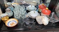 Collection of assorted glassware, pottery, and china including mugs, vases, plates, bowls, and serving dishes displayed together